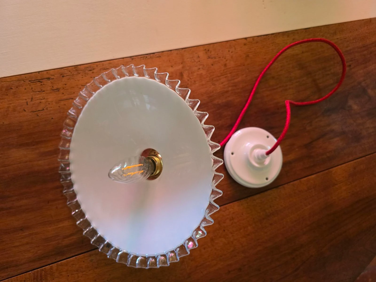 Lámpara de techo con disco opalino blanco y bordes transparentes sobre cable rojo y plafón de porcelana – photo 4